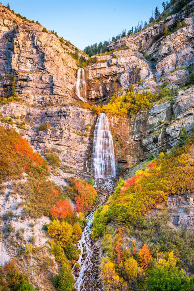 Tall waterfall flowing off the mountains during fall.