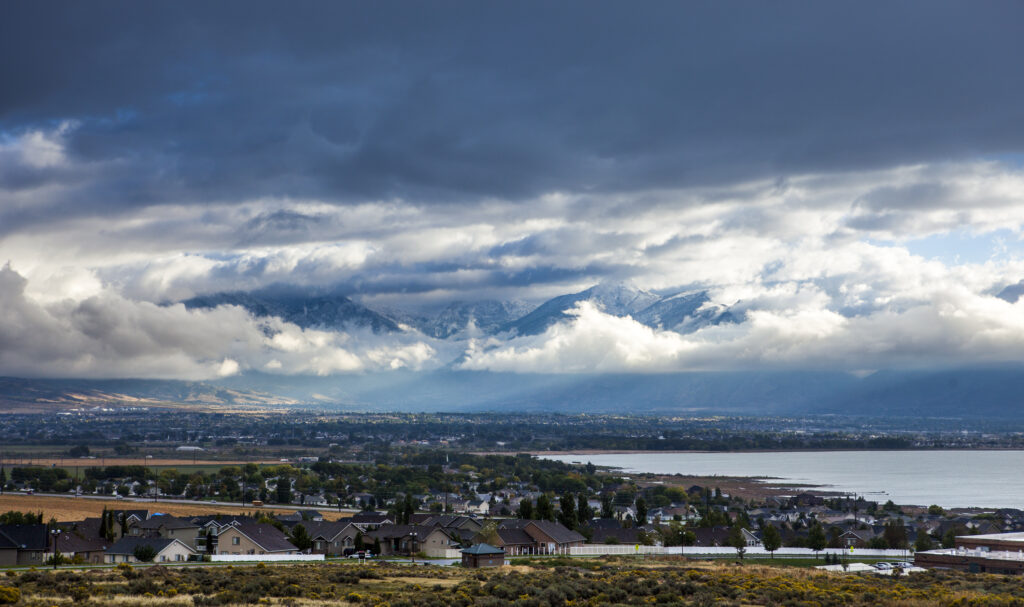 Landscape with suburbs, a large lake, and mountains in the background.