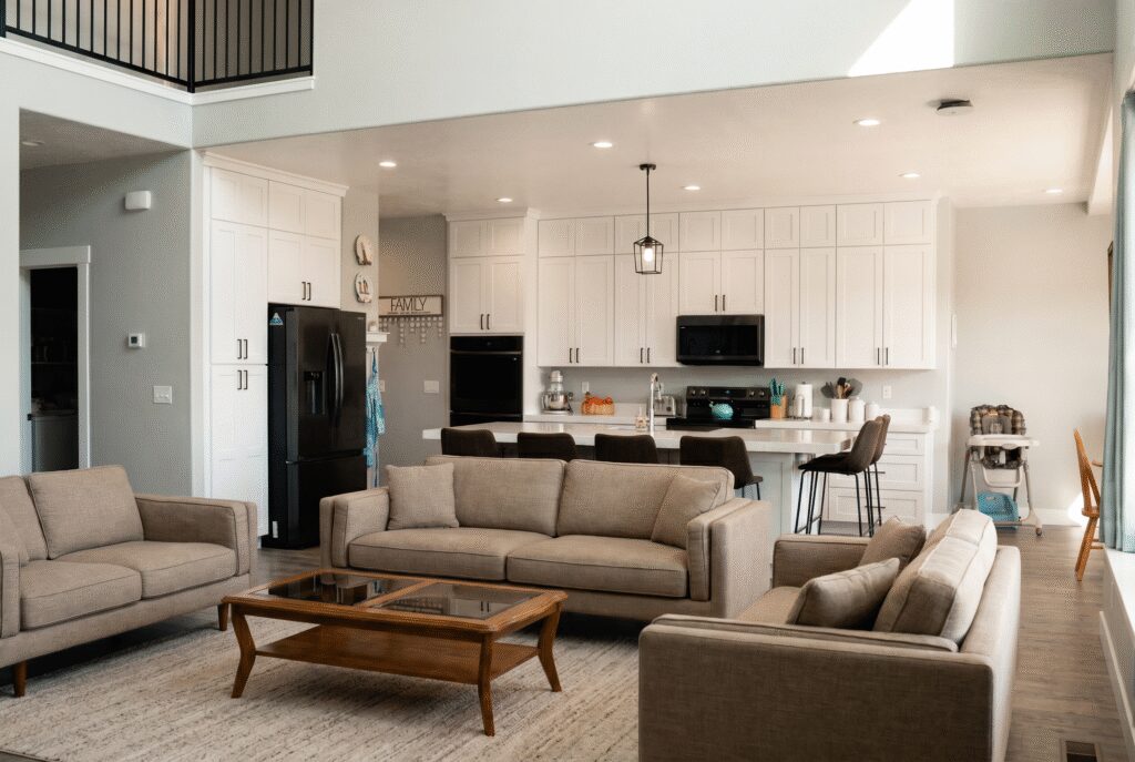 Open concept kitchen and living room with white cabinets, island seating, and comfortable sofa.