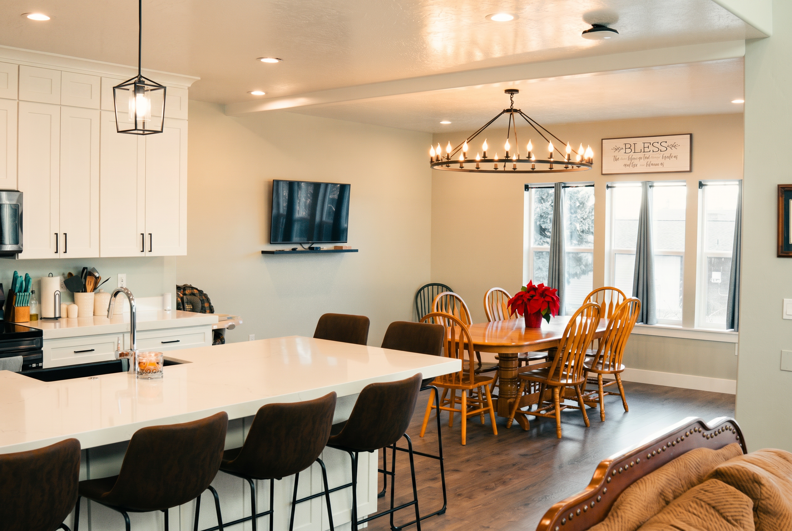 Open concept kitchen and dining room with white cabinets, island seating, and 'BLESS' sign.