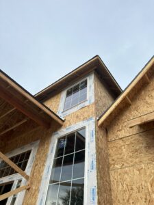 Under-construction house with exposed plywood and installed windows.