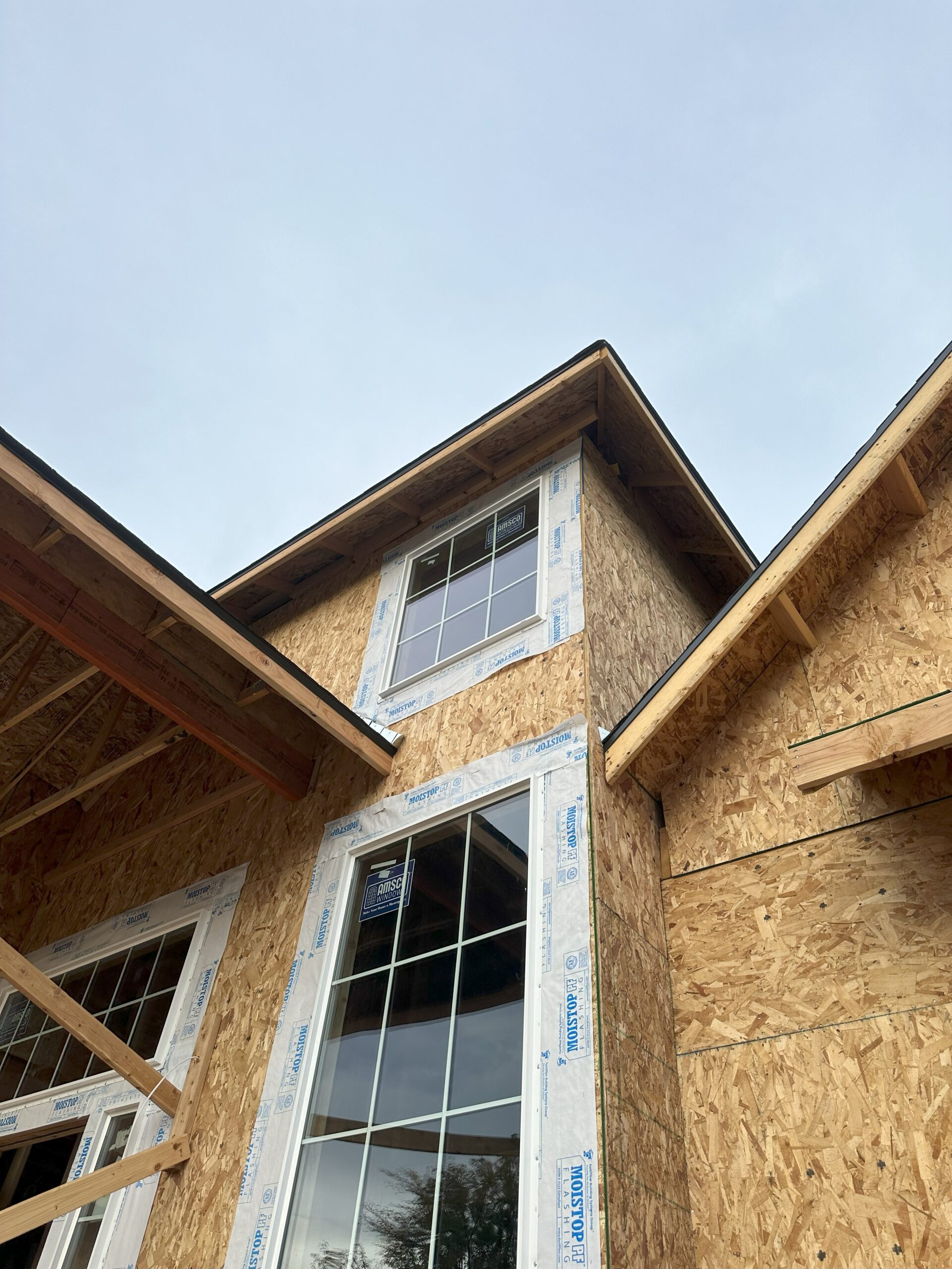 Under-construction house with exposed plywood and installed windows.