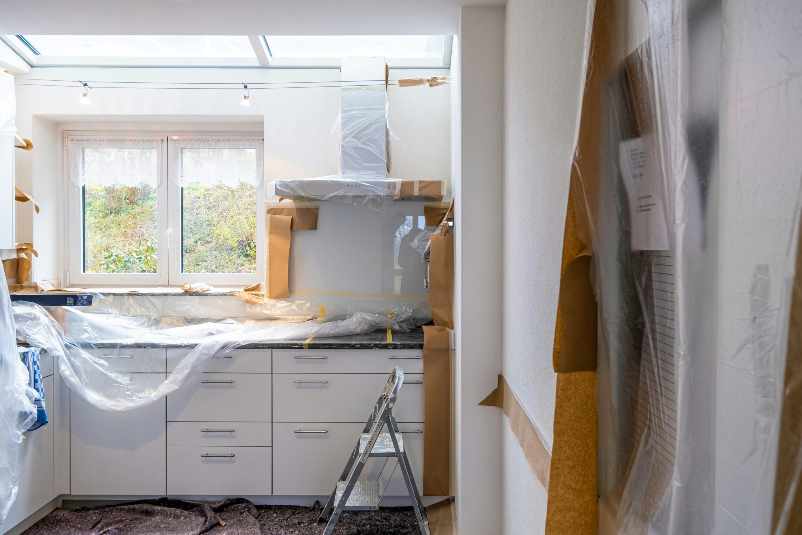 Kitchen renovation in progress showing protected cabinets and skylights during home remodeling project.