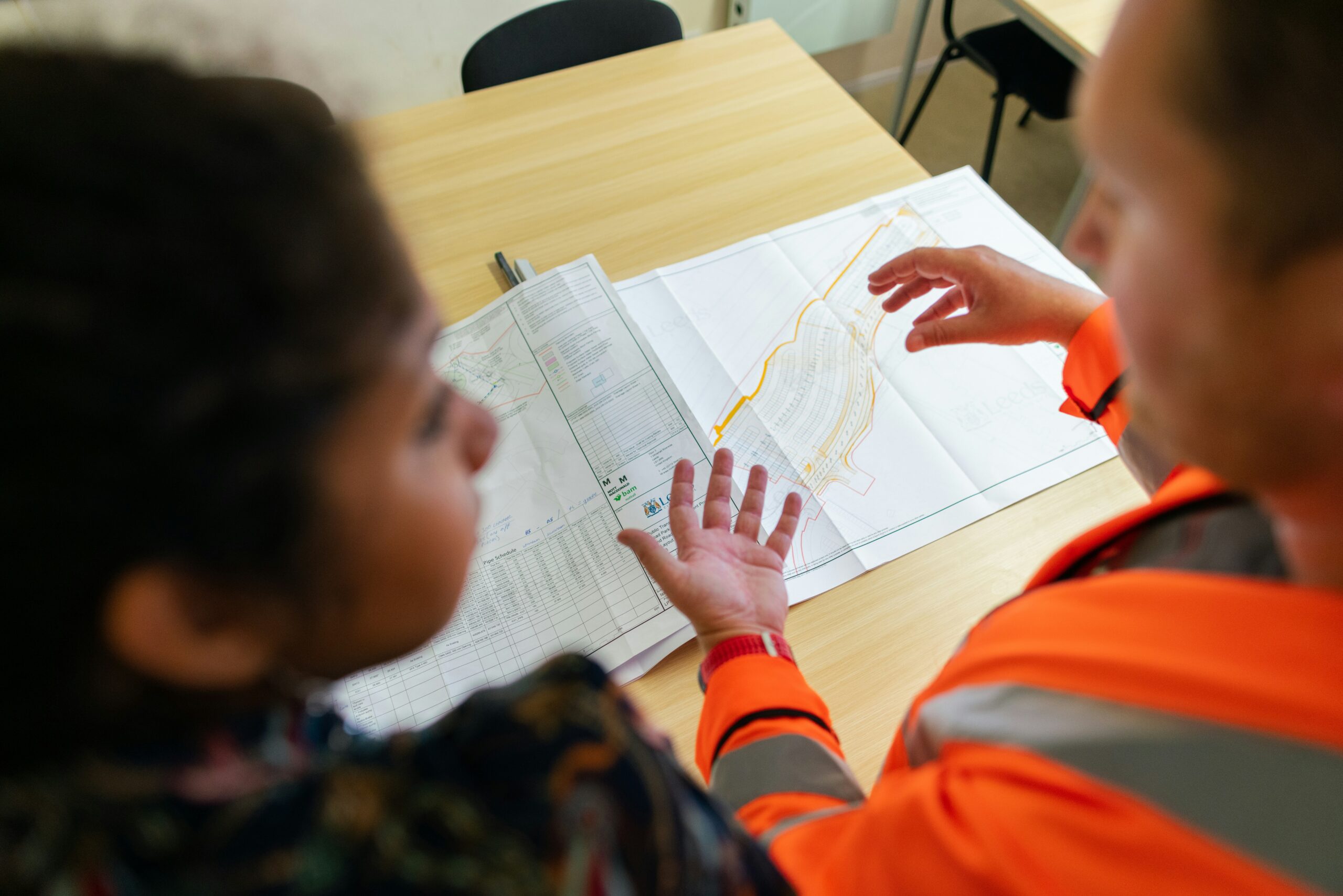 Builder and homeowner reviewing custom floor plan designs during a consultation.