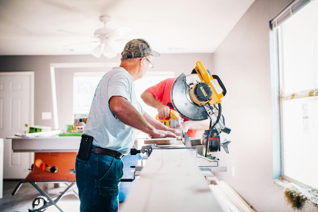 Two Utah home builders cutting wood indoors with a saw during a custom home project.