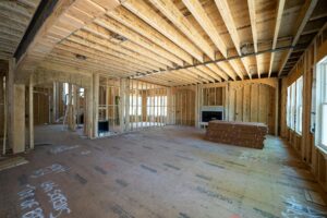 Framed interior of a new home under construction, showing wood beams, open layout, and natural light.