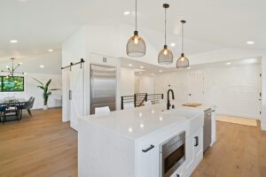 Modern renovated kitchen with white cabinets, pendant lighting, and a large quartz kitchen island.